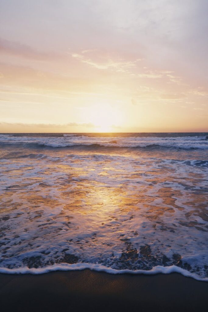 Capture the serene beauty of Bali's beach sunset with golden reflections on the ocean waves.